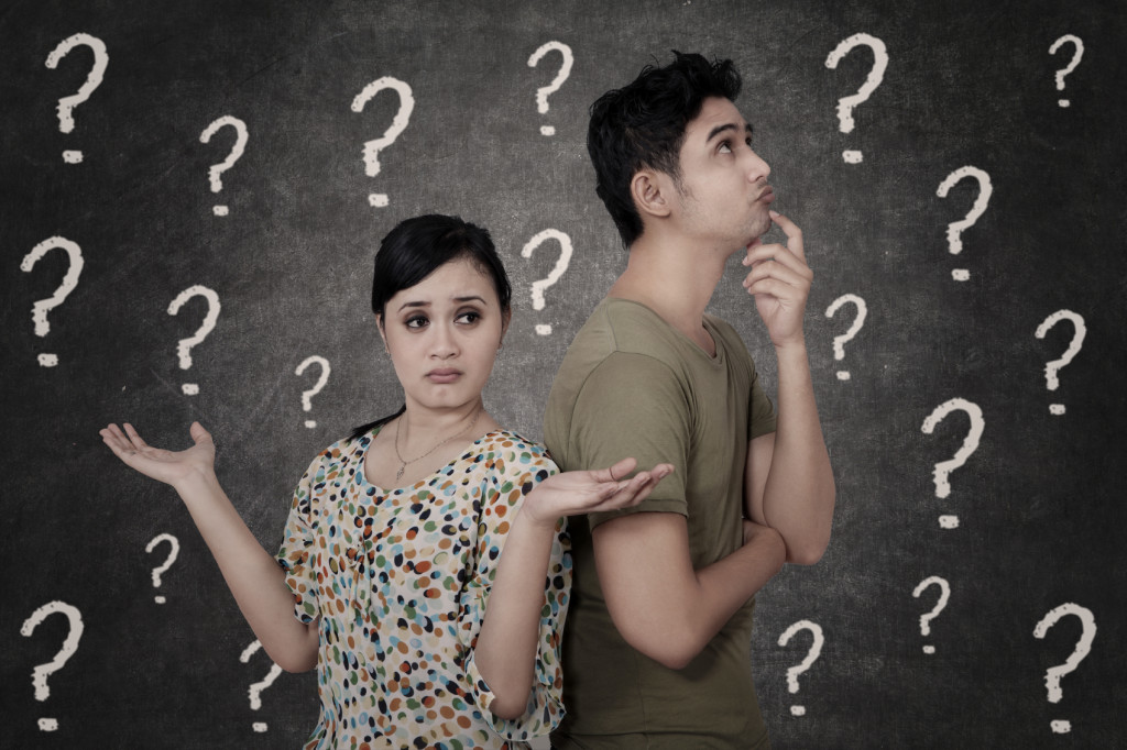 Confused couple with question marks on blackboard