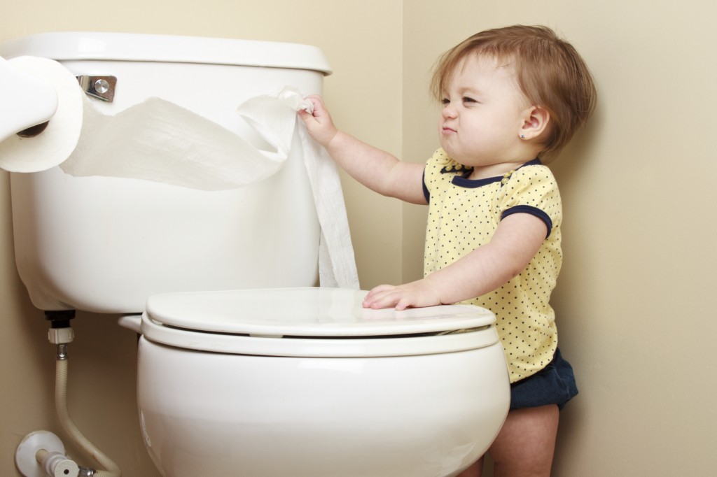 Ornery baby pulling toilet paper off the roll