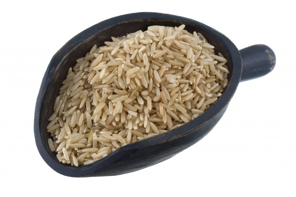 fragrant basmati brown rice on a rustic wooden scoop, isolated on white