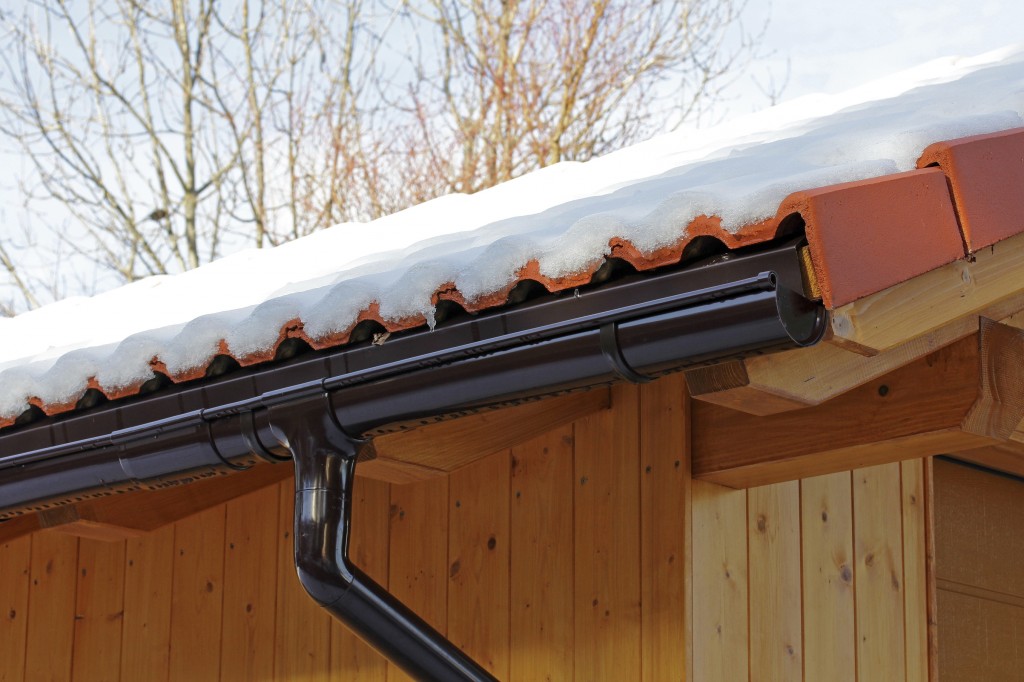 wooden roof with rain gutter and drainpipe in winter